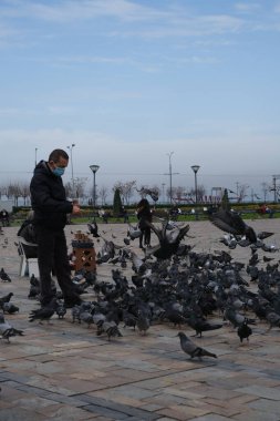 İzmir, TURKEY-Şubat 3. 2021: İzmir Konak Meydanı. Adam güvercinleri besliyor.