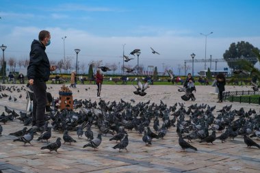 İzmir, TURKEY-Şubat 3. 2021: İzmir Konak Meydanı. Adam güvercinleri besliyor.