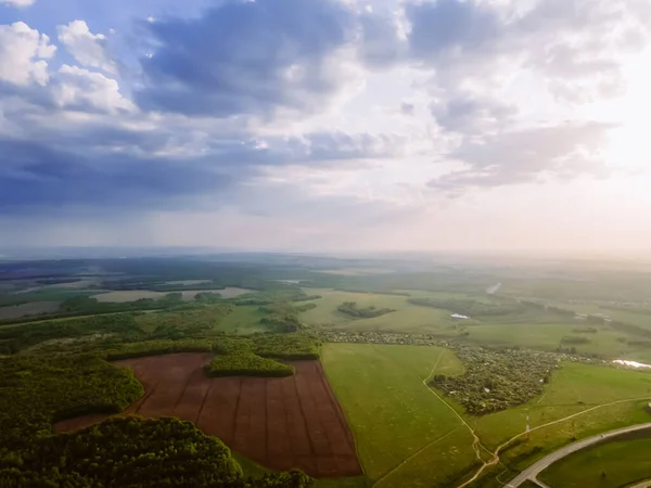 Birds-eye view of a summer landscape with fields and sky. Its raining in the distance. View from the drone.