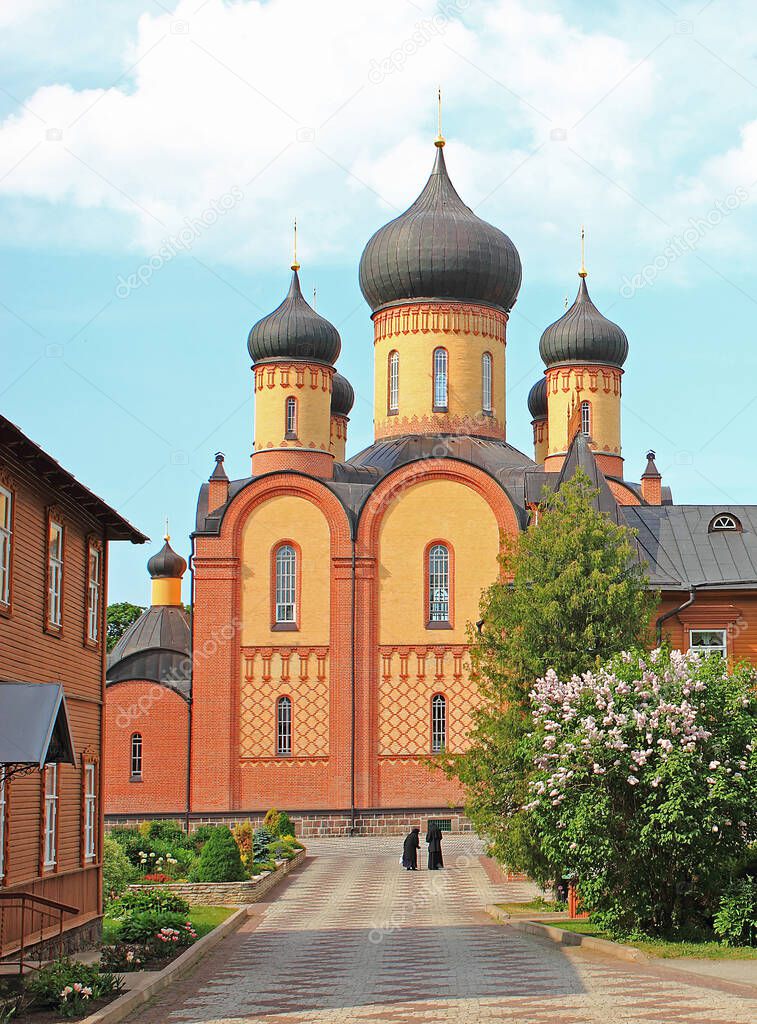 View of inner courtyard of Phtitsa Dormition Convent in Estonia. Old sisters are going to sunday morning prayer to Dormition Cathedral.