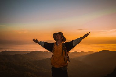 İnsanlar gün batımı dağlarında gölgelere tırmanıyor. Sırt çantaları dağın tepesinde. Güzel gökyüzü manzarasına, özgürlük kavramına bakıyorlar..