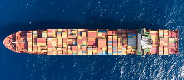 Açık denizlerde yüzen büyük konteynır kargo gemisinin yukarıdan aşağıya havadan çekilmiş fotoğrafı.