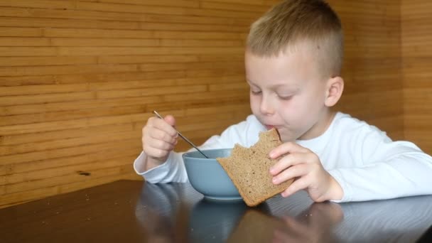Παιδί τρώει μεσημεριανό και κρατάει γκρι ψωμί στο χέρι του — Αρχείο Βίντεο