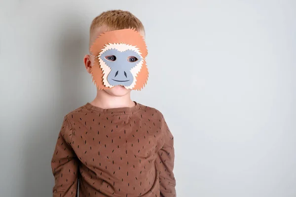 Máscara de un animal mono en la cara de un niño. aislado sobre fondo gris — Foto de Stock