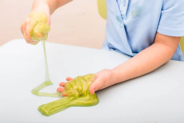 Mucus in the hands of a child sitting at a table — Stock Photo, Image