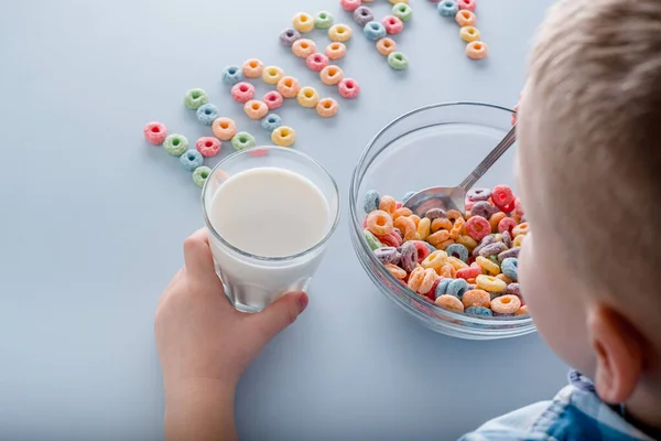 Das Kind isst ein Frühstückszerealien. Wort mit Kornschleifen glücklich auf blauem Hintergrund. — Stockfoto