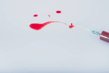 Mavi arka plandaki şırıngadan bir damla kan. Kanlı üzgün emoji. Yüksek kalite fotoğraf