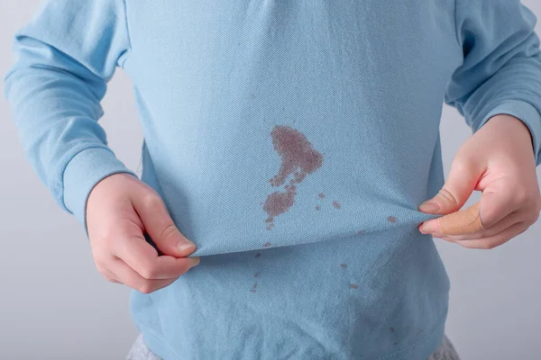 child showing a stain on his clothes. The concept of cleaning stains on clothes. Isolated on a white background. High quality photo