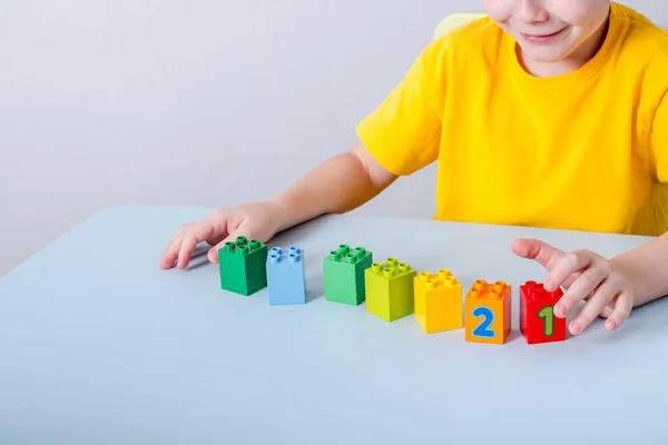 Barnet leker med kuber med färgglada siffror på bordet. På en vit bakgrund. — Stockfoto