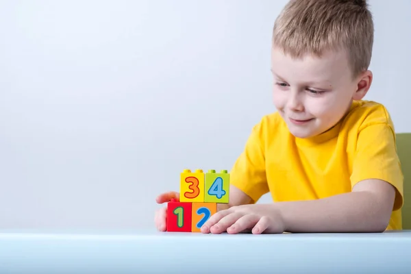 El niño jugando con cubos con números en la mesa.En un fondo blanco.Concepto de los desarrolladores de niños pequeños —  Fotos de Stock