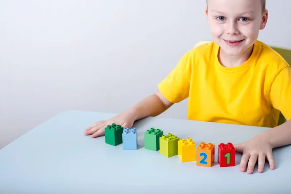 Barnet leker med kuber med färgglada siffror på bordet. På en vit bakgrund. — Stockfoto