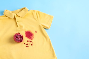 Çamaşırların üzerine meyve suyu sıçratır. Günlük hayat, çamaşır yıkama ve temiz konsept için kirli lekedir. Mavi arka planda izole edilmiş. Üst Manzara. Yüksek kalite fotoğraf
