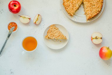 Elmalı turta ve bir fincan çay, beyaz masa arkasında elmalar. Ev yapımı klasik meyveli turta. Boşluğu kopyala, üst görünüm
