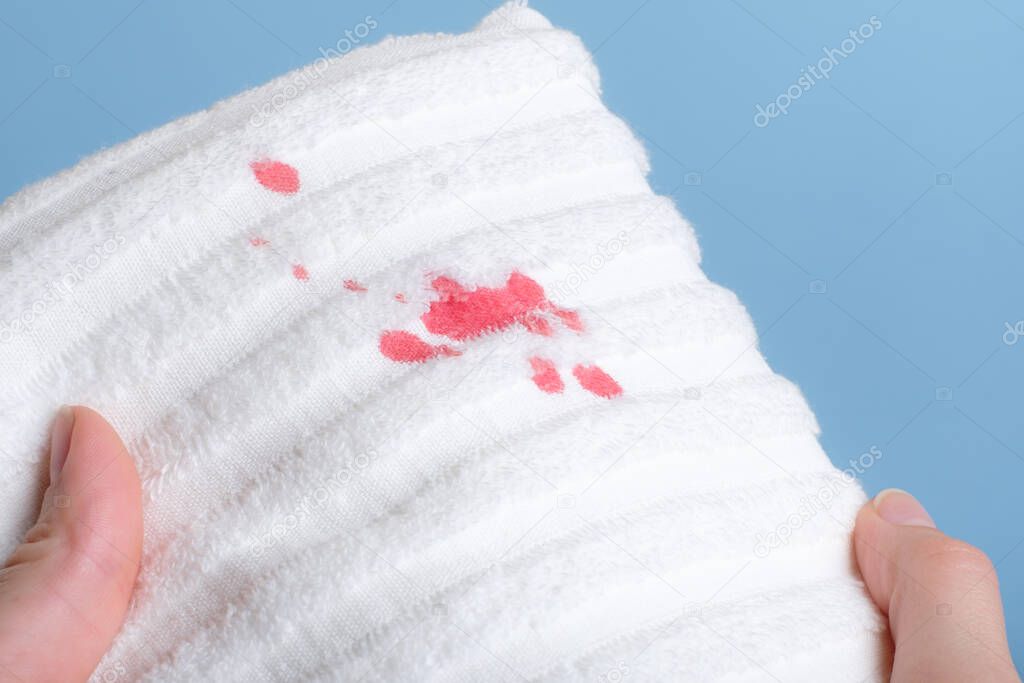 Hands holding a towel with blood stains. daily life dirty stain for wash and clean concept. High quality photo