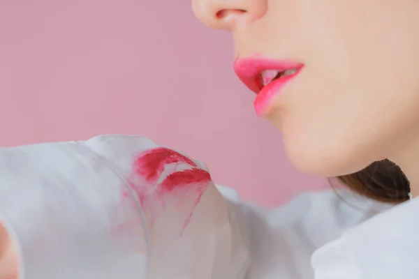 흰 셔츠를 입은 한 여성 이 립스틱에 묻은 더러운 얼룩. 분홍빛 배경에 고립됨 — 스톡 사진