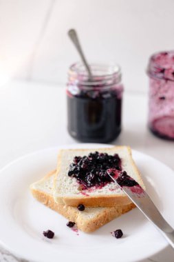 Böğürtlen reçeli tostun üzerine bıçakla yayılıyor. Sabah kahvaltısı ve ev konforu kavramı. Üst Manzara. Yüksek kalite fotoğraf
