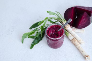 Bir kavanoz ev yapımı pancar turpu humusu. Ortasında bir kaşıkla. Beyaz arka planda izole edilmiş organik yiyecekler. Üst Manzara. Yüksek kalite fotoğraf