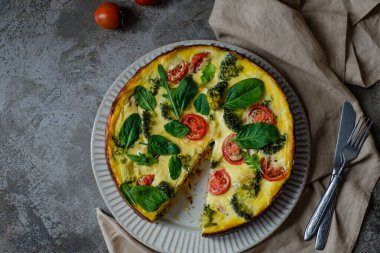 Kiş lorraine turtası geleneksel ev yapımı Fransız yemeği tarifi peynirli domates brokoli ve pastırmalı, koyu ahşap masa arkasında. Yüksek kalite fotoğraf