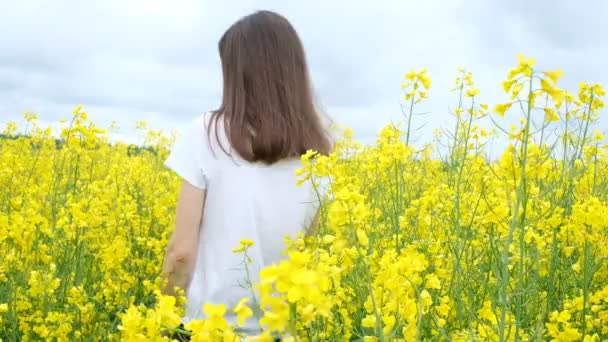 Jeune femme en t-shirt blanc parmi un champ de fleurs jaunes — Video