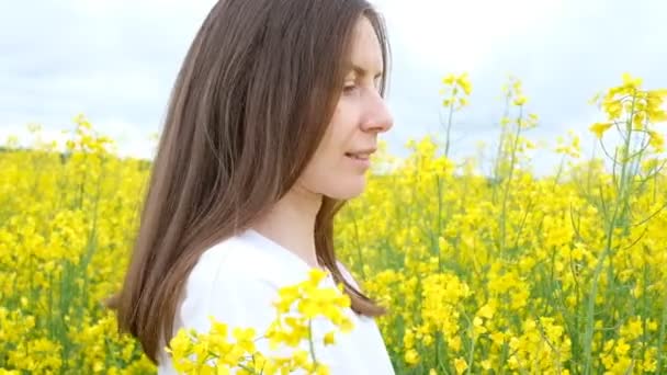 Красива дівчина без макіяжу, з широкою посмішкою в полі серед жовтих квітів — стокове відео