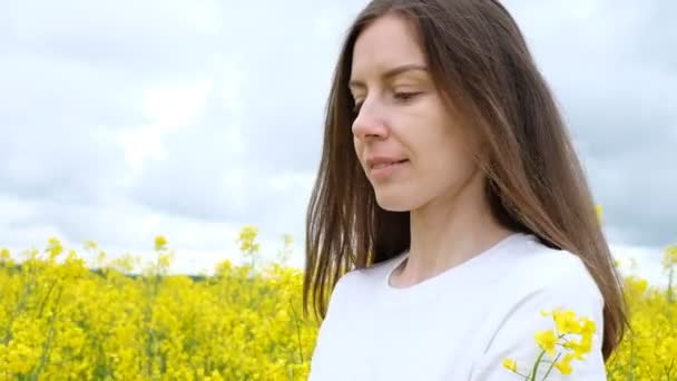 Portrait d'une femme aux cheveux longs et au large sourire dans un champ de fleurs jaunes — Video