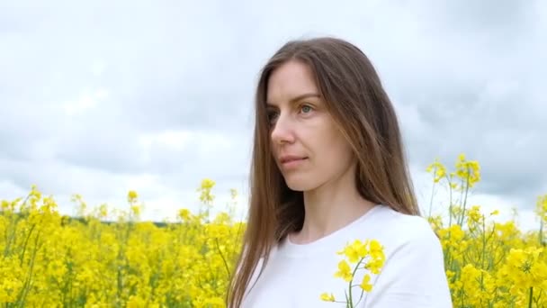Портрет жінки з довгим волоссям і широкою посмішкою в полі жовтих квітів — стокове відео