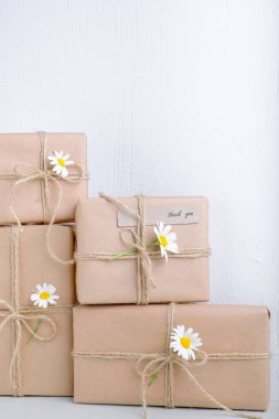 Kahverengi el işi kağıdıyla sarılmış ve doğal papatya çiçekleri ile süslenmiş hediye kutuları. Metin için boşluk. Yüksek kalite fotoğraf