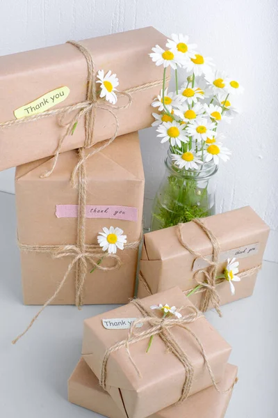Kahverengi el işi kağıdıyla sarılmış ve doğal papatya çiçekleri ile süslenmiş hediye kutuları. Metin için boşluk. Yüksek kalite fotoğraf