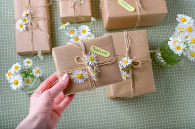 Çiçeklerle süslenmiş kraft kağıdına sarılı hediye ya da hediye paketi tutan kadın ve teşekkür kartları. Yüksek kalite fotoğraf