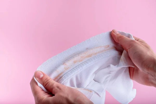 Kadın elleri beyaz bir gömleğin yakasında kirli bir leke gösteriyor. Pembe arka planda izole. Yüksek kalite fotoğraf