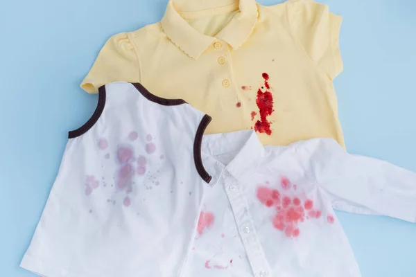 Dirty stains of juice and blood on children's clothes. Laundry collection.isolated on blue background, top view. dirt stains for cleaning and washing concept. High quality photo