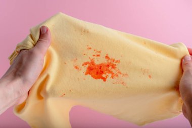 Female hands showing bright stain on clothes. daily life dirty stain for wash and clean concept. isolated on pink background. High quality photo