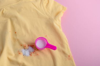 Stain on clothes. washing powder in a plastic spoon. removal of stains from spilled drink. dry cleaning concept. High quality photo clipart