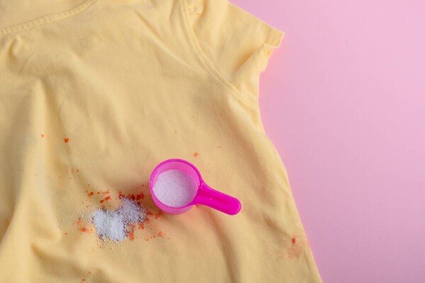 Stain on clothes. washing powder in a plastic spoon. removal of stains from spilled drink. dry cleaning concept. High quality photo