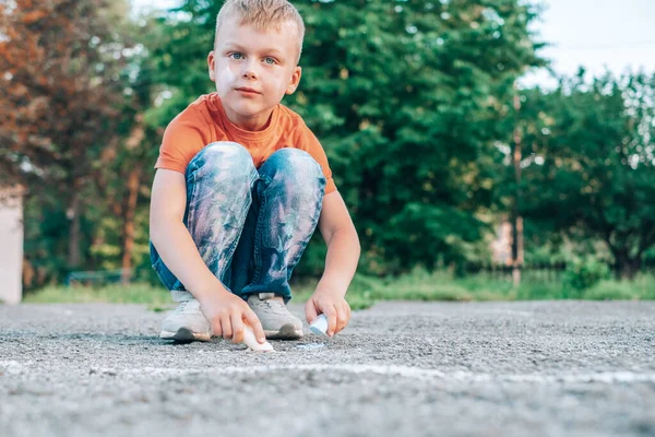 Boy with both hands draws a rainbow on the sidewalk. The concept of cleaning stains on clothes. High quality photo