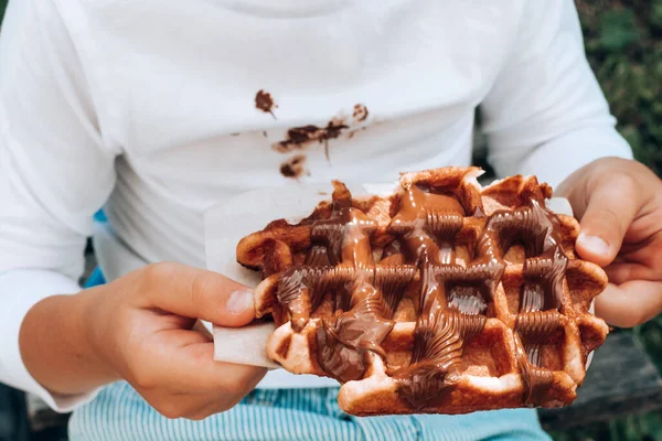Çocuk elleri çikolata soslu Belçika waffle 'ı tutuyor. Kapat. Yüksek kalite fotoğraf