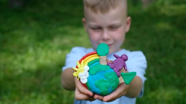 Main d'enfant tenant le modèle de terre avec arc-en-ciel en argile. concept d'écologie. vue de dessus — Video