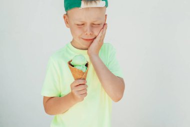 Dondurma yiyen ve diş ağrısı çeken bir çocuğun portresi. Diş bakımı, sağlık hizmeti konsepti. Yüksek kalite fotoğraf