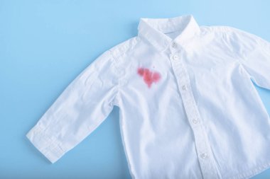 Meyve suyu beyaz bir gömleğe döküldü. Mavi arka planda izole edilmiş. Yüksek kalite fotoğraf