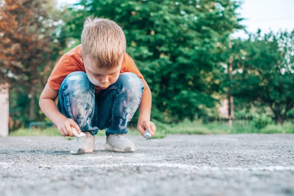 The child drawing on the sidewalk. The face and clothes are stained with chalk. — Stockfoto