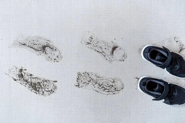 Brudne buty zostawiające błotniste ślady na dywanie. widok z góry — Zdjęcie stockowe