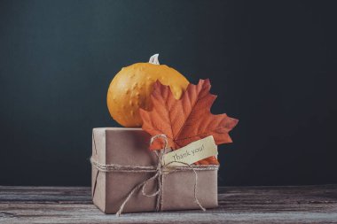 Kahverengi balkabağı kağıdına sarılmış ve sonbahar yapraklarıyla süslenmiş bir hediye kutusu. Minnettarlık sözleriyle. Yüksek kalite fotoğraf