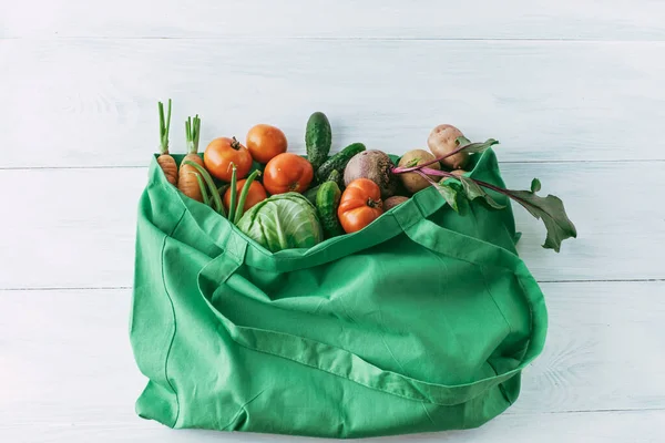 Green shopping bag with grocery products on white background. top view — Stock Photo, Image