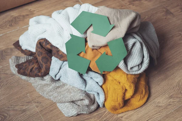 Régi őszi ruhák a padlón otthon és kartonpapírból kivágott újrahasznosító tábla. Újrahasznosítási koncepció. — Stock Fotó