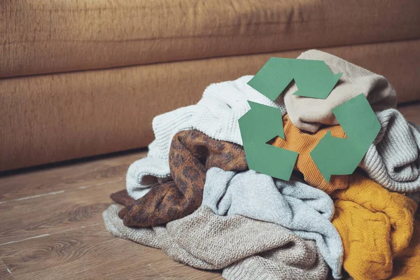 Pilha de roupas antigas de outono no chão de casa e reciclar sinal cortado de papelão. Reciclar conceito de roupas. — Fotografia de Stock