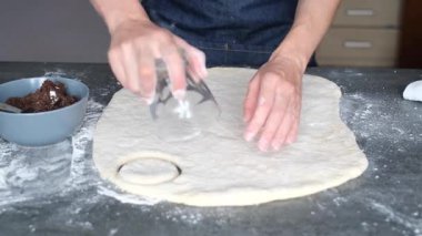 Bir insan mutfak tezgahında kurabiye hamuru hazırlar. Yuvarlak hamur parçaları kesiciyle kesiliyor. Un kolay taşımak için etrafa yayılır. Malzemeler yakında. Yüksek kalite 4k görüntü