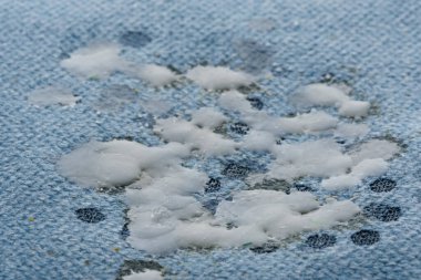 Beyaz mum kumaşa ya da mavi arka planda mobilya döşemelerine damlıyor. Sıcak bir yerde mavi arkaplan ve lekeler yaratıyor. Günlük yaşam sorunu ve ev temizliği kavramı.