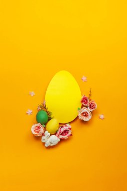 Paskalya bayramı konsepti, el yapımı beyaz yumurtalar, sarı arka planda çiçekler. Düz konsept, üst görünüm. Metin için bir paskalya kartı ve yerin bir kopyası..