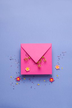 Paskalya tebrik kartı, güzel el yapımı renkli yumurtalar, kraft pembe zarf ve leylak arkaplanda çiçekler. Düz konsept, kopyalama alanı olan üst görünüm.