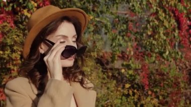 Şapkalı kadın güneş gözlüğünü çıkarıyor.